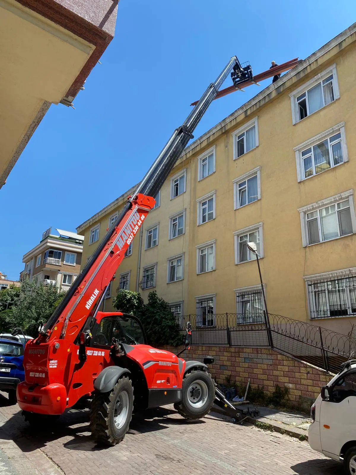 Manitou teleskopik yükleyici apartmanın üst katına malzeme uzatıyor