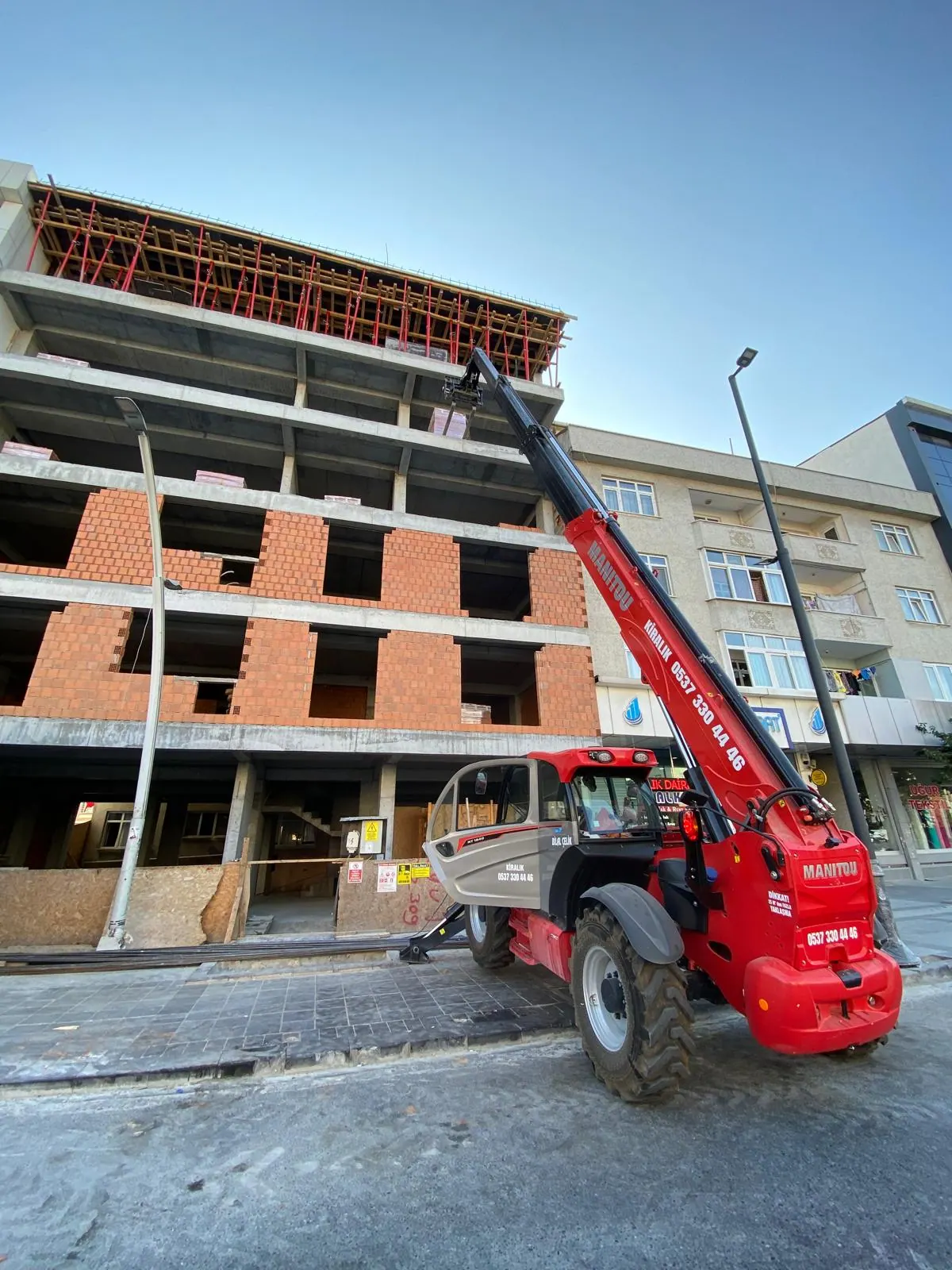 Kaba inşaattaki binaya malzeme taşıyan Manitou